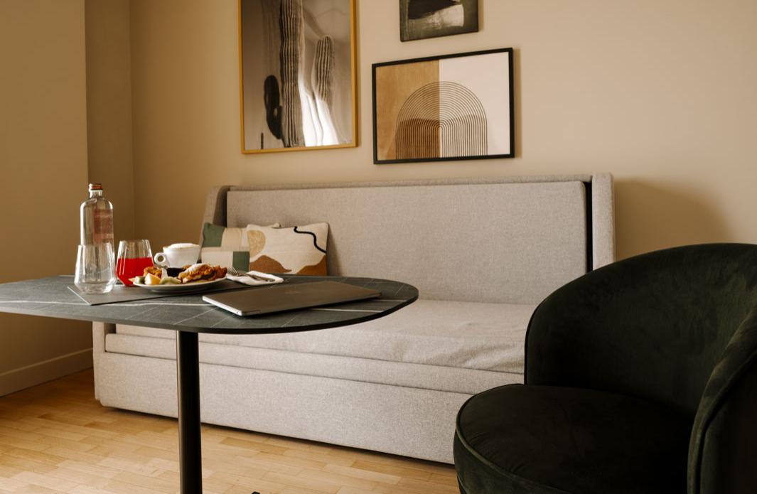Soggiorno moderno con divano grigio, tavolo nero e opere d'arte minimaliste.