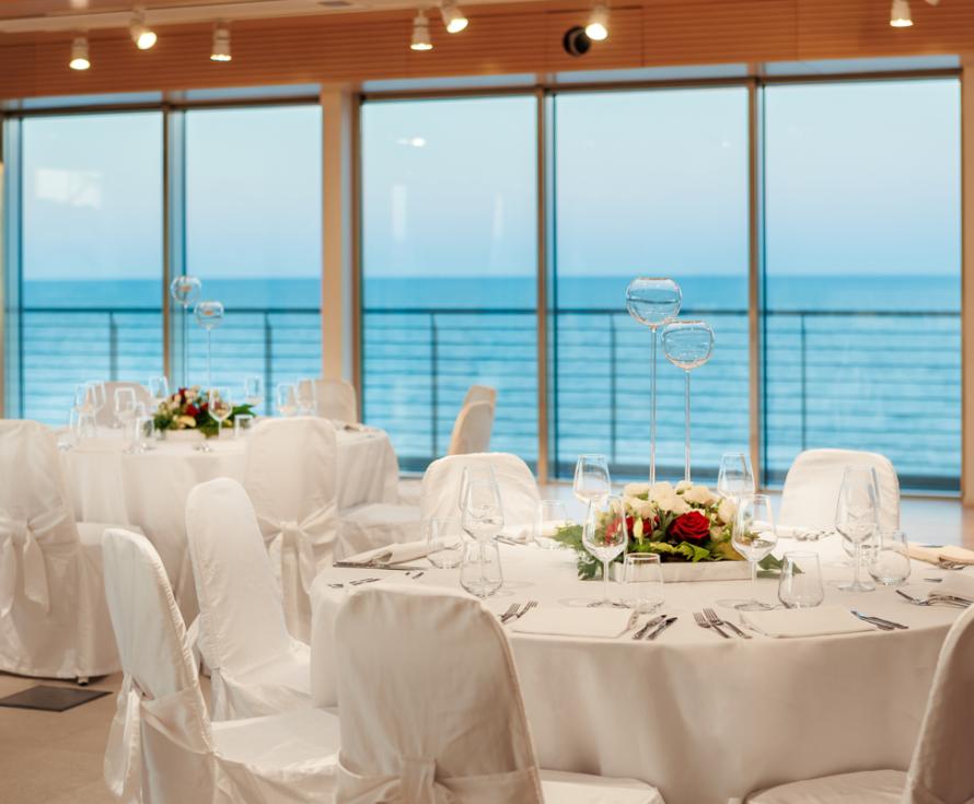 Sala elegante con vista mare, tavoli apparecchiati.